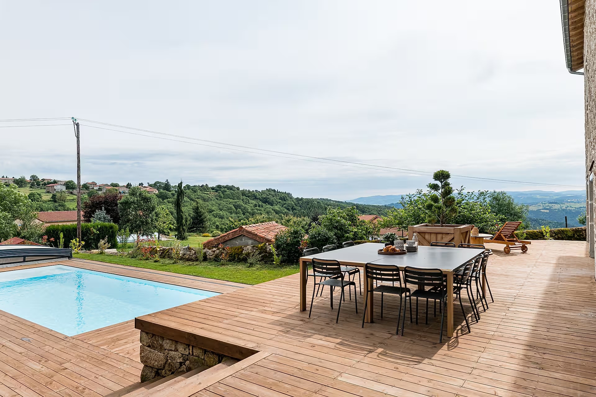 Terrasse en bois et grande table face aux collines